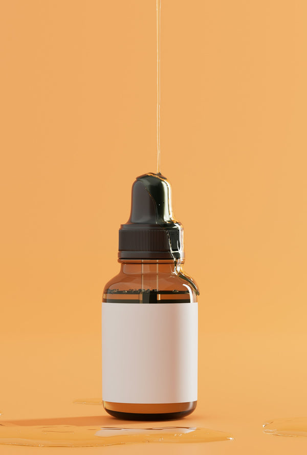 Amber glass dropper bottle with a blank label on a warm orange background